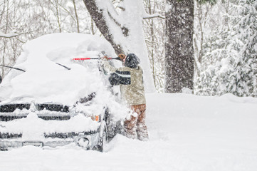 man clearing snow off his truck during a winter blizzard