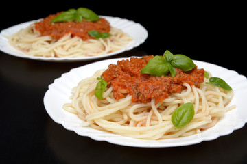 Two dish pasta with bolognese sauce on black