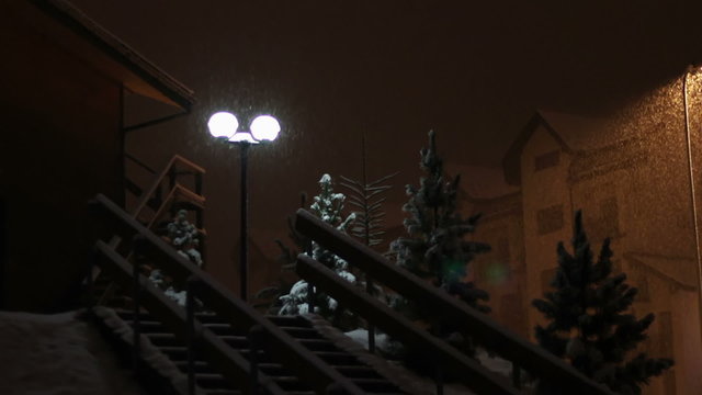 Snowing at night on the background of a lamppost.