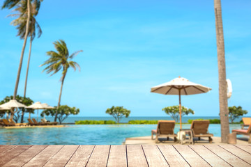 Wooden table with blurry tropical sea and resort background.