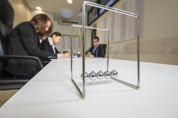 Young business people group have meeting and working. Close up on a Newton pendulumn