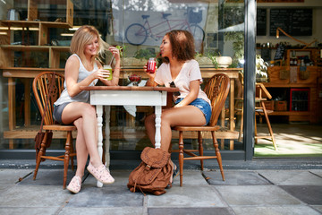 Two happy women at cafe enjoying drinks and chat