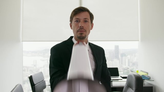 Corporate manager standing with megaphone in modern office. The man screams loud with energetic expression and crosses arms in portrait pose. Medium shot