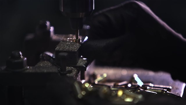hands rapidly changing details in the boring machine. It looks like a bullet or bullets for the weapon. Factory production of weapons and ammunition, ammo