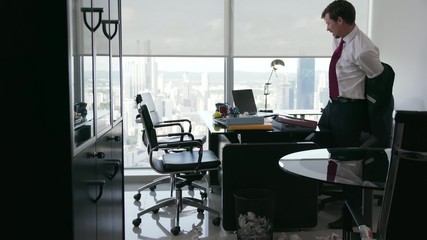 Corporate manager in modern office tries to write a job letter. The man is frustrated and keeps on screwing up paper. He feels anxious and take off his jacket. Wide angle shot - Powered by Adobe