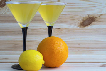 Two cocktail glasses and fresh citrus fruit on a wooden background