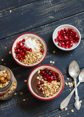 Healthy Breakfast - yogurt with homemade granola and pomegranate on a dark wooden board. Top view
