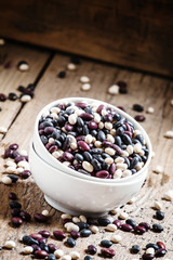 Speckled beans in white china bowls on an old wooden background,