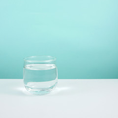 The small round glass of pure water on a white table.