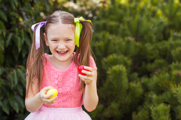 Cute little girl with 2 pigtails playing in the park, egg hunting