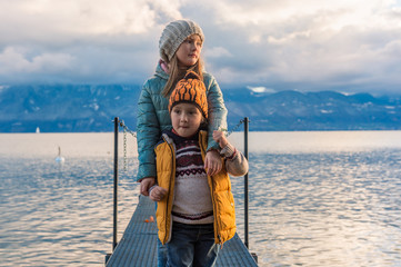 Fototapeta na wymiar Late evening portrait of two adorable kids playing by the lake Geneva, Switzerland