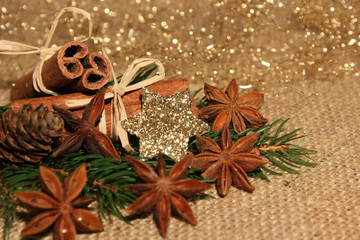 Weihnachtliche Dekoration mit Sternanis, Zimtstangen, Tannenzapfen, Tannenzweigen und Glitzerstern
