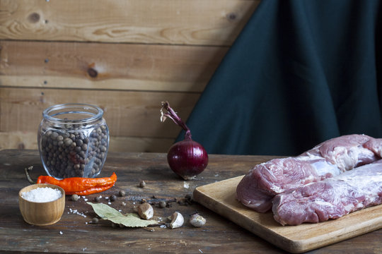 Raw pork fillet with spices and vegetables on the wood background