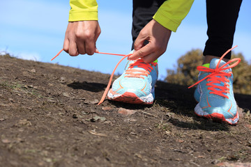 Fototapeta na wymiar young woman trail runner tying shoelace on mountain peak