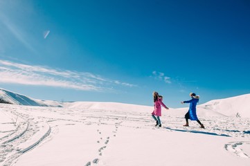 Fototapeta na wymiar winter, two cheerful young girls having fun in the snow in the m