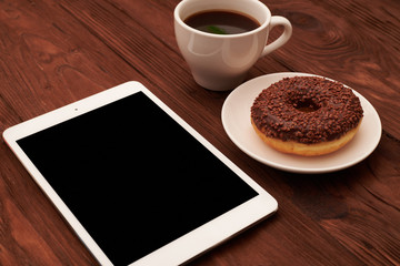 Fototapeta na wymiar tablet pc, chocolate donut and cup of coffee