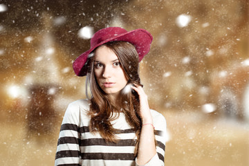 Thoughtful young lady in red floppy hat on winter background 