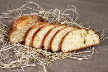 sliced white bread lying in straw on grey linen tablecloth