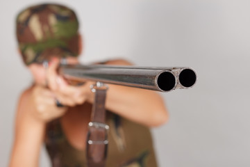 Woman hunter with a gun take aim. Gray background