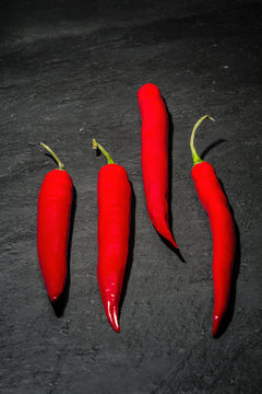 Drei rote Peperoni auf einem Untergrund aus dunklem Naturschiefer