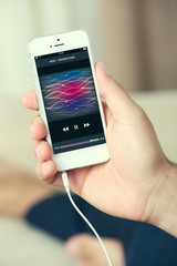 Music smartphone in male hand, on home interior background