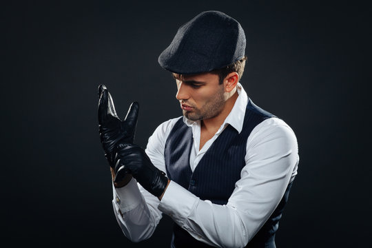 Handsome man in a vest and cap wears leather gloves in studio Stock Photo |  Adobe Stock