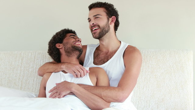 Homosexual couple speaking together on bed