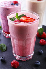 Milkshakes at cutting board with berries on light background
