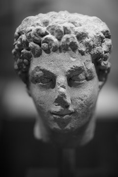 Damaged male face of an ancient statue, monochrome