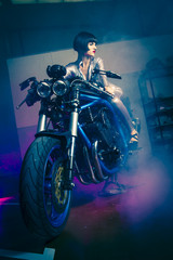 travel, brunette with latex suit mounted on a bike with a modern