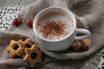 Cup of hot cacao with cookies and nuts on cotton serviette