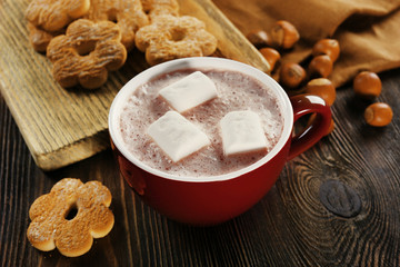 Cup of hot cacao with cookies and nuts on wooden kitchen board, close up