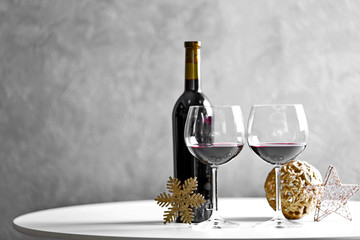 Red wine and Christmas ornaments on wooden table on wall background