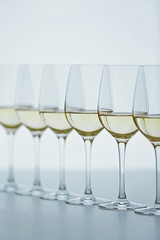 Wineglasses with white wine on wooden table on bright background