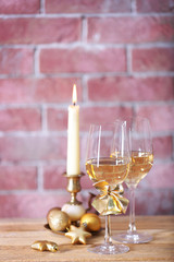 Two glasses of wine with candle and Christmas toys on wall background