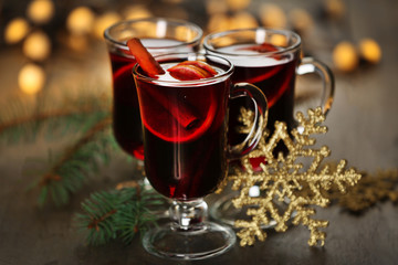 Mulled wine with spices and Christmas tree on wooden background