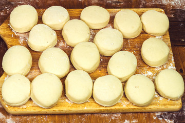 Fototapeta na wymiar Small balls of fresh homemade dough on floured wooden board