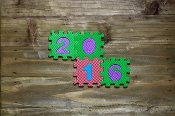 Puzzle block letter with numbers 2016 on wood background