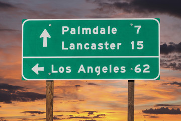 Naklejka premium Palmdale, Lancaster and Los Angeles Highway Sign with Sunset Sky