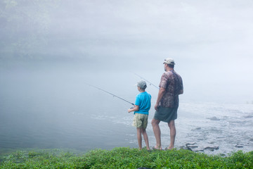 Father and son in the early misty morning fishing