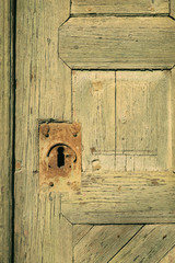 Old, vintage cellar wood door with a rusty and decorated keyhole