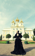 Beautiful woman in black dress posing next to the palace.