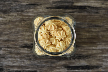Butter cookie in glass bottle open on wood background (Top view)