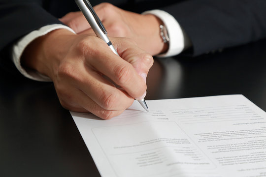 Businessman's Hand holding a pen signing to the document