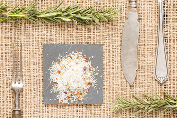 Salt with spices on dark plate with rosemary, antique forks, spo