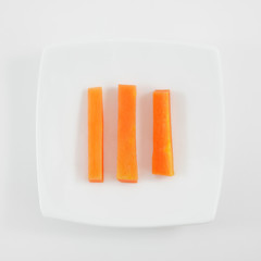 The three fresh orange carrot sticks on the white small dish.