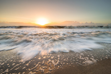 The rising tide rushing in towards land on Edisto Island, South Carolina during the sunrise. - 97254305