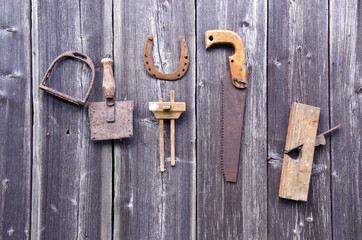 Old rusty tools hanging on grey wooden wall