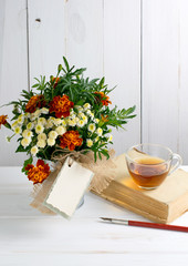 Tagetes flower bouquet with decorative greeting card and old boo