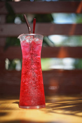 Red soda water in a glass with blur wooden background
